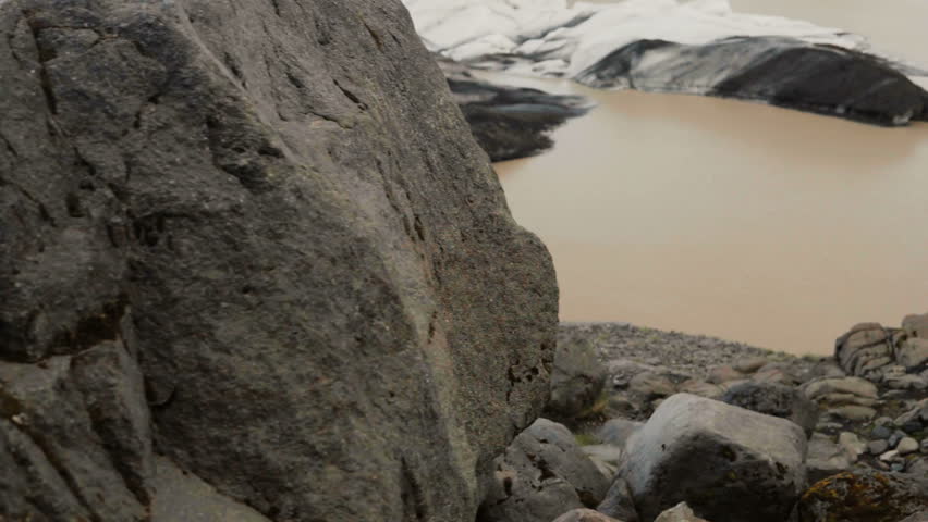 Young traveling woman hiking in the Vatnajokull glaciers ice lagoon, walking through the rocks in the mountains.