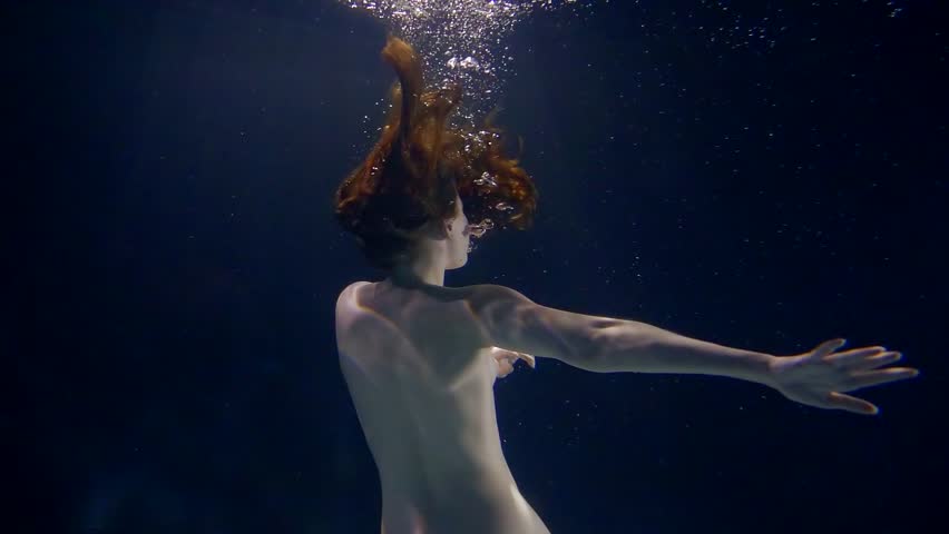 redhead young slim naked woman is spinning under water, long hair is waving