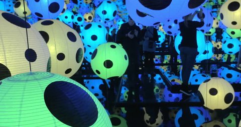 HELSINKI, FINLAND - JANUARY 07, 2017: Woman and kid walking in Infinity Mirrored Room - Hymn of Life. Balls with polka pattern changing colors in the dark. Yayoi Kusama exhibition