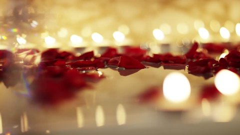 red rose pettles floating on waters surface with tealight candles in background