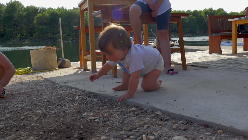 baby boy and little older girl playing with sand at sea shore. mother sitting near by watching over them. in slow-motion hd