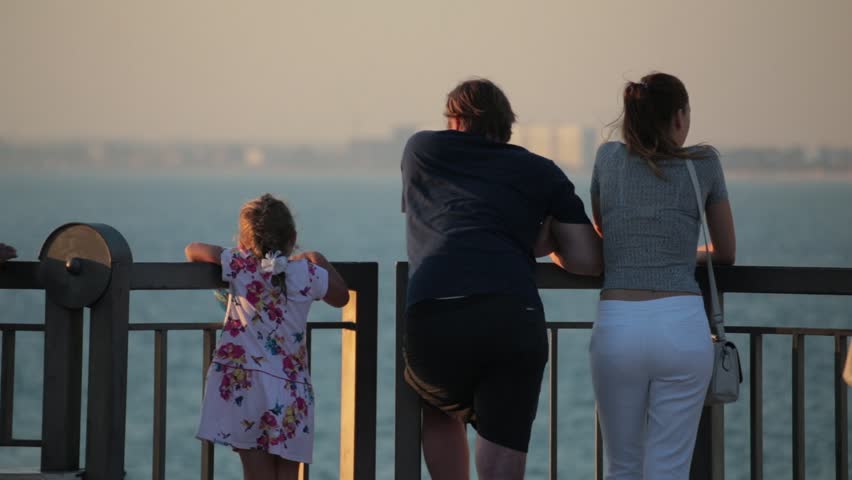 Back view of a family viewing the sea on the embankment.