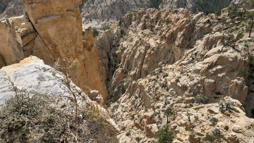 TILT UP-Rugged rock formations of the Box-Death Canyon Wilderness Area in the Boulder Mountains of southern Utah with gray clouds and patches of blue sky-4K 60p