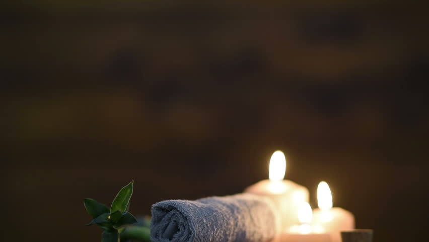 Brown towels with bamboo and candles for relax spa massage and body treatment. Beautiful composition with candles, spa stones and salt on wooden background. Spa and wellness setting with massage oil. | Shutterstock HD Video #30974698