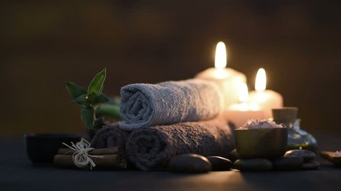Brown towels with bamboo and candles for relax spa massage and body treatment. Beautiful composition with candles, spa stones and salt on wooden background. Spa and wellness setting with massage oil.