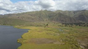 Flying drone and making Aerial View of Epic Mountains, Sky, Clouds, Field, Swamp and Lake. The shot was made in the Peruvian Andes.