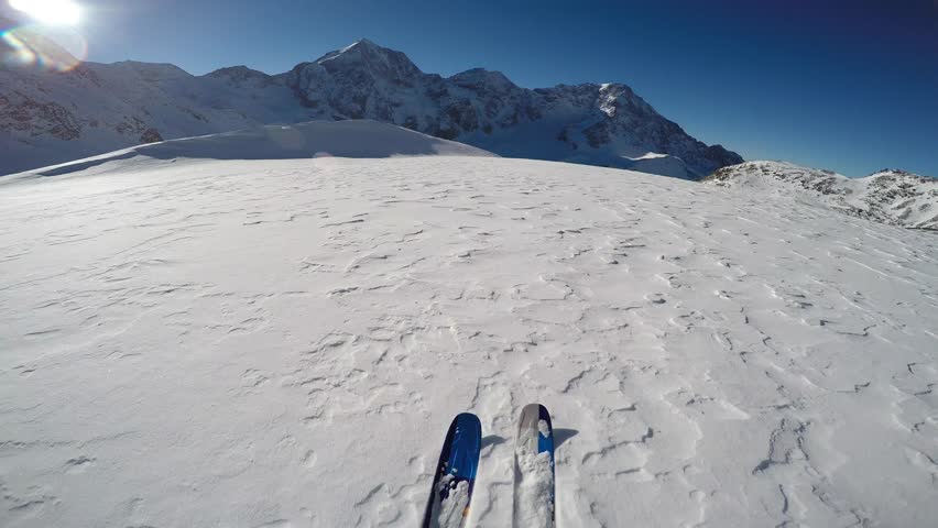 Mountaineer backcountry skiing along a snowy ridge. In background blue cloudy sky and shiny sun and Tre Cime, Drei Zinnen in South Tirol, Dolomites, Italy.  Adventure winter extreme sport.