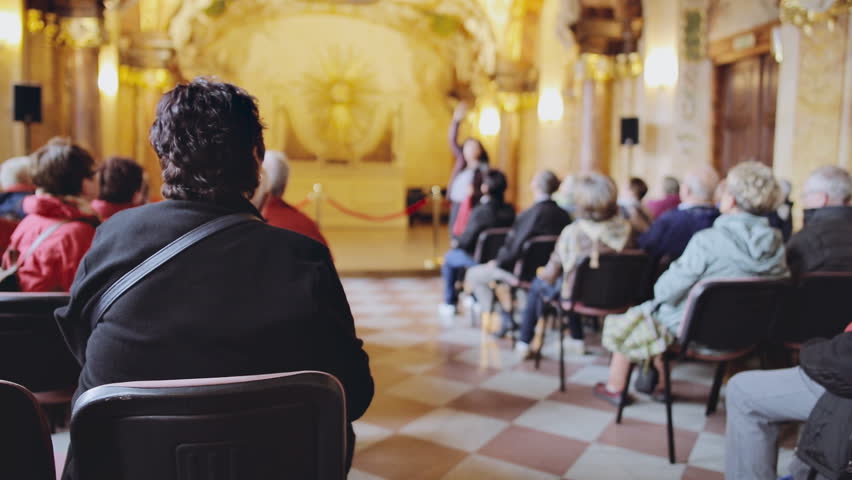 Group of foreign tourists on an excursion listens to their guide in ancient church