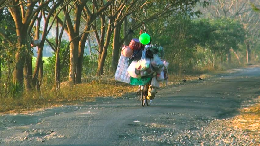 Vendor Man on bicycle with carrying balloons and handicrafts at a roadside