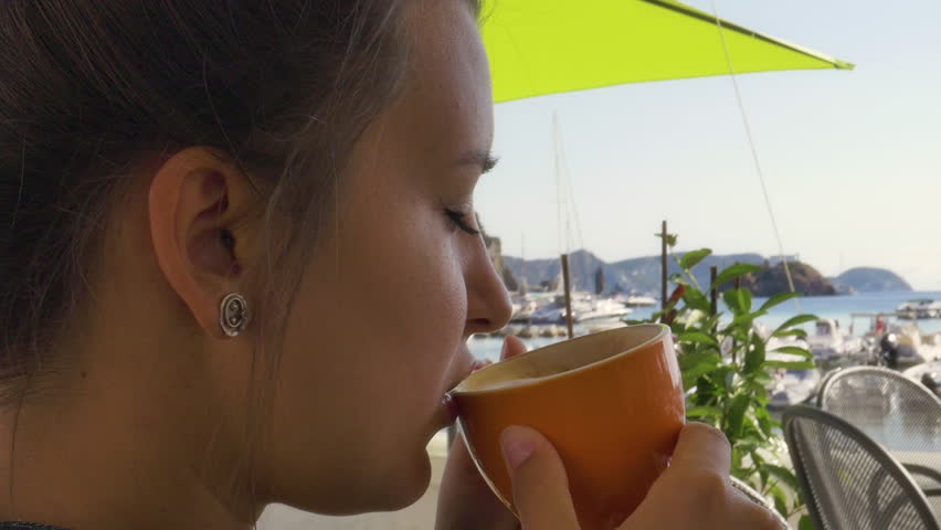 Woman drinking coffee sitting at the bar in front of the harbour on Ponza Island Italy