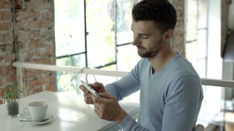 Handsome man playing game on smartphone and losing it, steadycam shot

