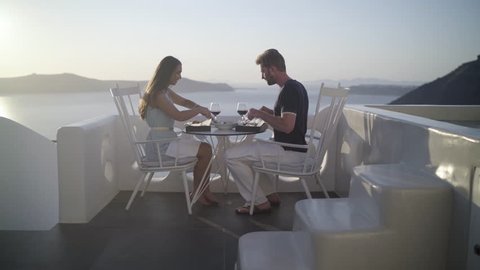4k travel video honeymoon couple eating burger with salad on romantic terrace outside on santorini island high up the caldera
