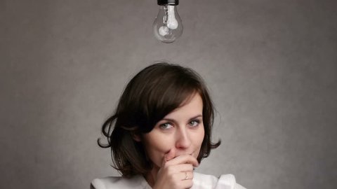 pensive woman gets an idea, which lights up a symbolic lamp over her head Stock Video
