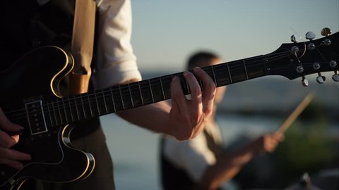close up shot of a musical instrument, which is called a rhythm guitar, a young musician performs energetic music in the daytime in the open air