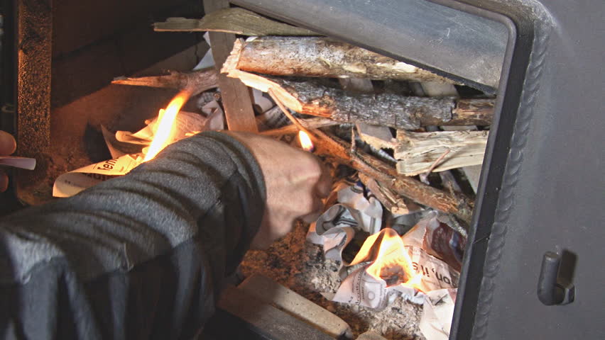 Lighting a fire in a wood stove with a match.