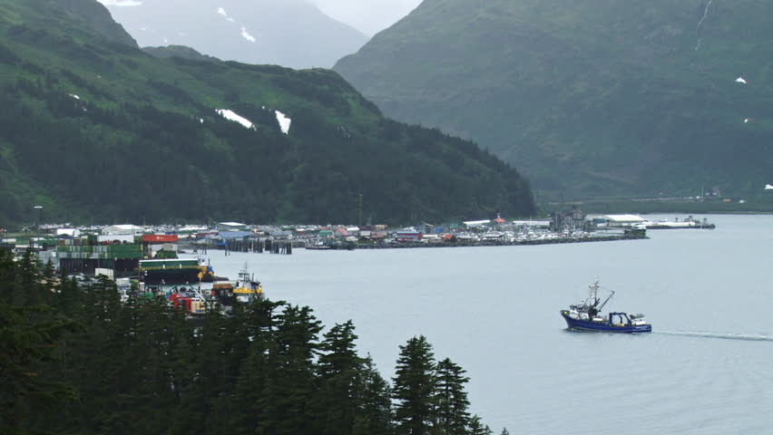 Wide shot of a large fishing vessel returning to port at Whittier, Alaska, on a