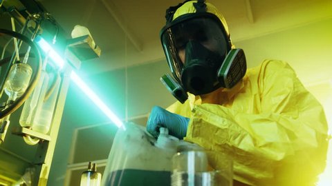 In the Underground Drug Laboratory Clandestine Chemist Wearing Protective Mask and Coverall Mixes Chemicals. He Pours Liquid From Canister into Bowl to Make New Batch of Synthetic Narcotics. 