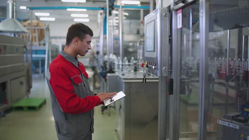 Production of drinking water, engineer working man adjusts production line machine control panel, automatic production.
