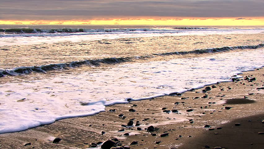 A glowing, colorful evening in Alaska, gentle waves slithering onto the beach