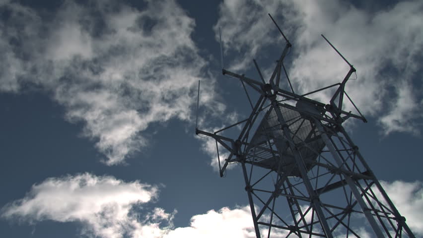 Ultra low-angle shot of a multiple antenna tower against time lapse cumulus