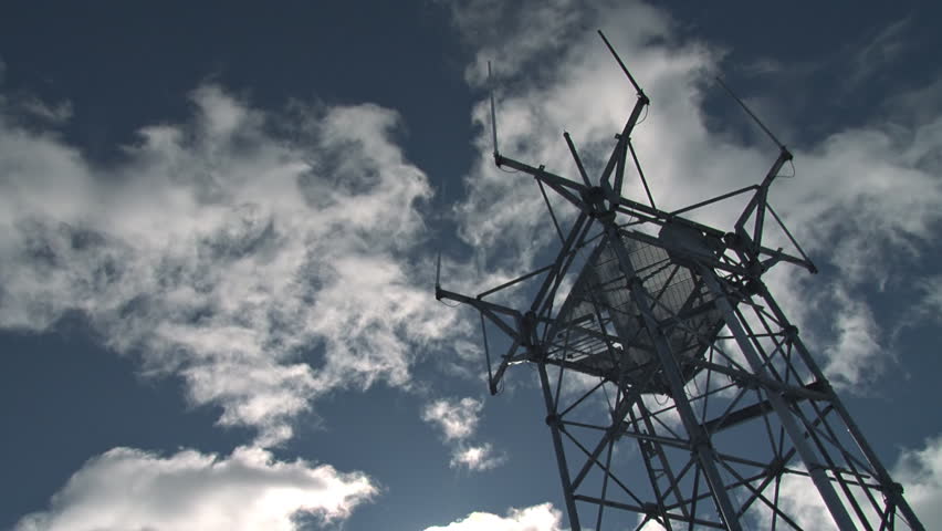 Ultra low-angle shot of a multiple antenna tower against real-time cumulus