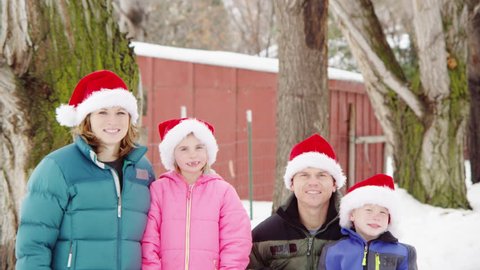 Family of four wearing santa hats, winter day.