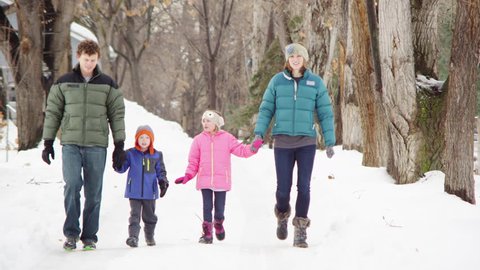 Family of four walking down a trail, winter day.