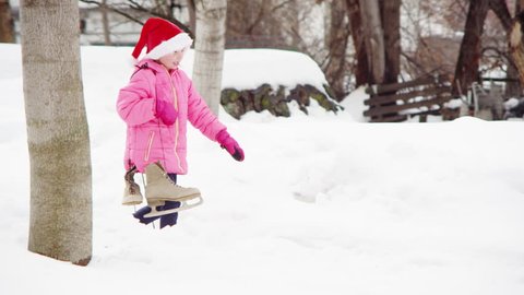 Young girl holding her ice skates, walking through the snow.