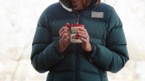 Woman drinking hot beverage outddors, winter day.