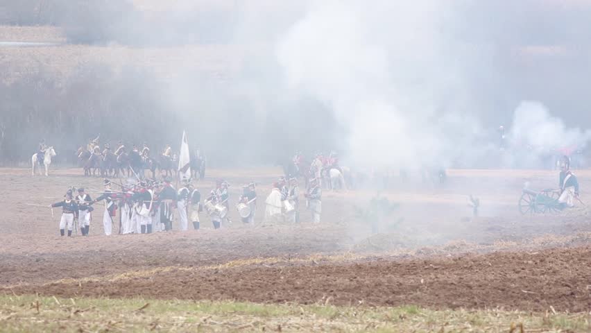 The troops of the Russian army are attacking, guns are firing, shells are exploding, smoke and fire of the battle, horse cavalry is galloping. Reconstruction of the war and the battle of 1812.