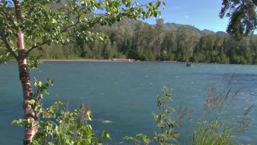 A group of fishermen in a small dory, floating down the Kenai River, trying to