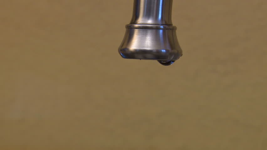 Wasteful dripping or leaking faucet, close-up. Medium-slow-paced drips with