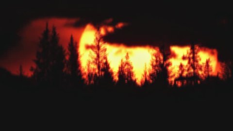 Forest fires rage across the lands, a shift in the wind brought smoke which enhanced this sunset caught at the end with heat waves and clouds, living and dead trees silhouetted, timelapse.