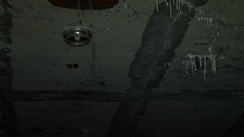 Pan shot from ruined, dripping, stalactite-encrusted ceiling with empty light