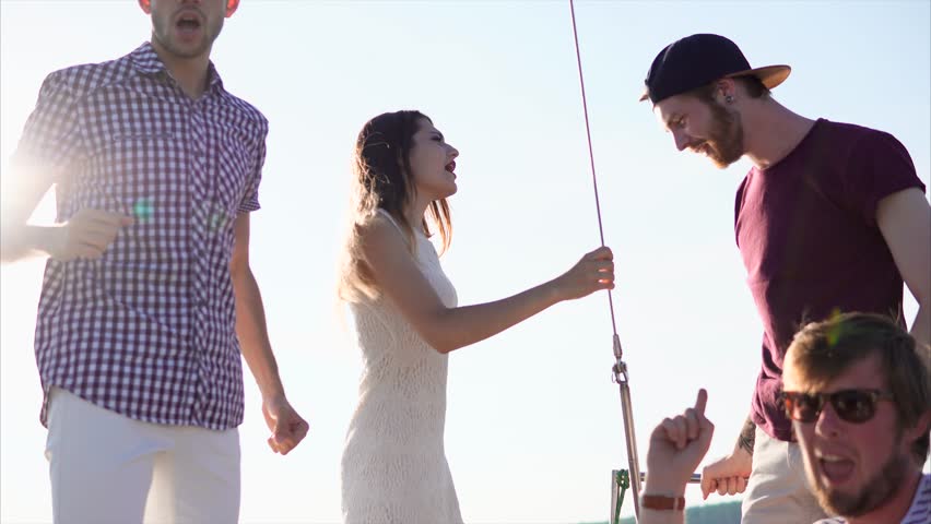 A company of modern and young friends who are on a yacht during the daytime dancing, men and women spend active laxhers vacation and enjoy warm summer days under energetic music