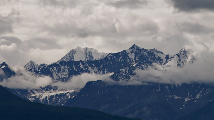 Time lapse of wickedly intense clouds roiling and flowing over peaks of the