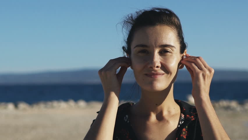 Portrait of a young woman who uses wireless earphones at ocean background. Slow motion 100 fps | Shutterstock HD Video #31016419
