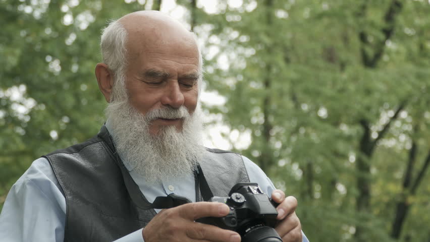 Gray-haired man photographs an autumn park