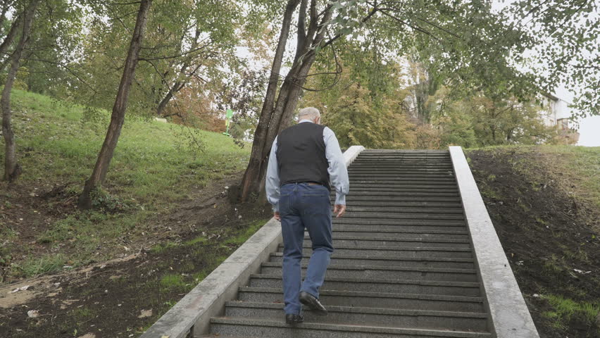Old man is going up the stairs in park