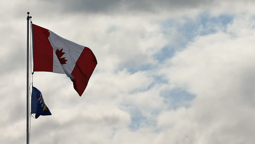 Proudly flying against a luminous cloudy sky, the flag of Canada