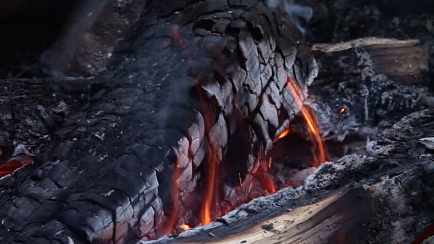 Tight shot of burning logs with smoke and flames in a campfire. Shot at 240fps,