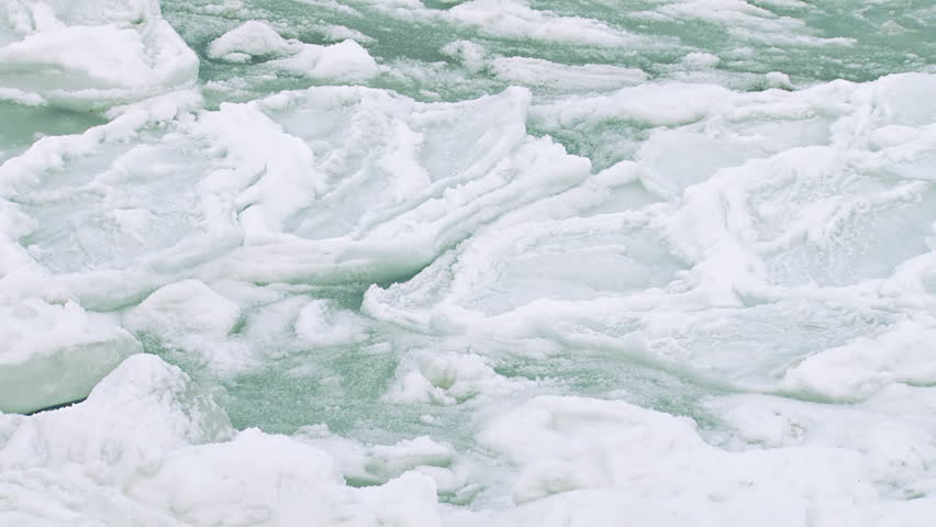 Close-up shot of broken sea ice on the bay, heaving slowly as if breathing as