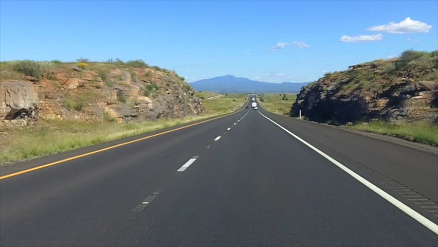 The point of view of someone driving Interstate 40 on a summer day near Seligman, AZ.