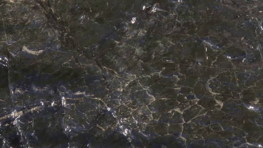 Black rock or coal striated with quartz with flowing water in a small creek by