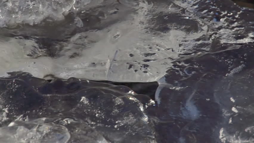 Pan in slow motion from gaping crevice in river ice with strangely shaped