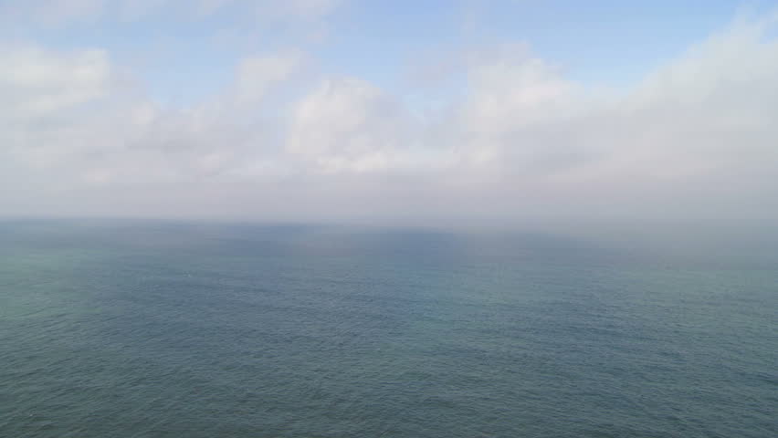 Wide shot of the Pacific Ocean with light misty morning clouds