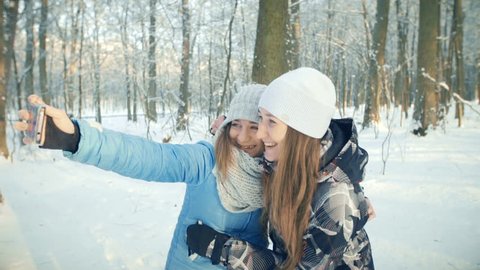 Girls take selfie in winter forest on san set. Girls  take selfie in winter forest. They like to take selfie.