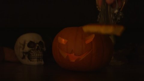 Carved Halloween pumpkin lights inside with flame and skuls around.