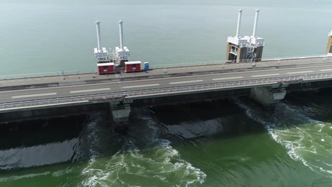 Aerial view of Eastern Scheldt storm surge barrier Oosterscheldekering flying right showing traffic driving over largest of 13 ambitious Delta Works series of dams and storm surge barriers in Zeeland
