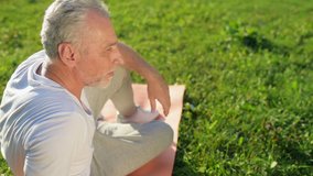 Delighted aged man resting after sport exercises in the park